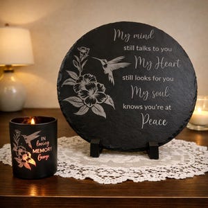 May include: A black memorial slate with a hummingbird and floral design, and the words "My mind still talks to you, My Heart still looks for you, My soul knows you're at Peace." A black candle with a hummingbird and floral design and the words "In loving memory George."