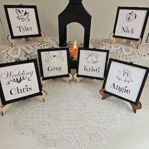 May include: A white ceramic mug with a black handle and the text "But First, Coffee" in a black, handwritten-style font. The mug is on a white surface.