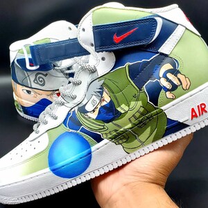 May include: White high-top sneakers with a green, blue, and black design featuring the anime character Naruto. The sneakers have a blue swoosh logo on the side and the word "AIR" on the back.