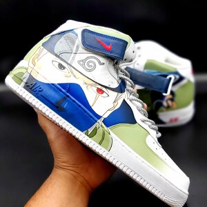 May include: White high-top sneakers with a custom design featuring an anime character with blue, green, and red details. The character's face is visible on the side of the shoe. The shoe has a white sole and a blue strap with a red Nike swoosh.