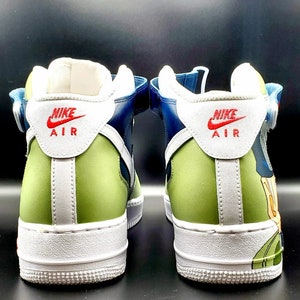 May include: A pair of blue and green high-top sneakers with white soles and a white swoosh logo. The sneakers have a strap across the top and the words "Nike Air" are printed on the back of each shoe.