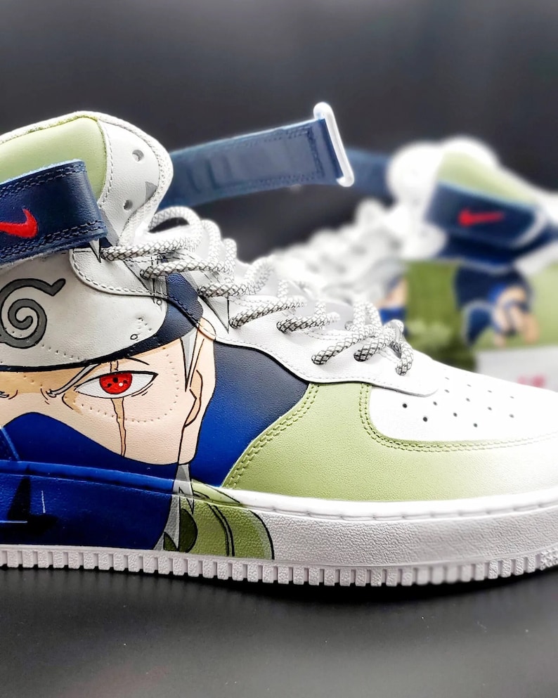 May include: Custom-painted high-top sneakers featuring a green, blue, and white color scheme with a detailed illustration of a character from the anime series Naruto. The character has a red eye and a white headband with a spiral symbol.