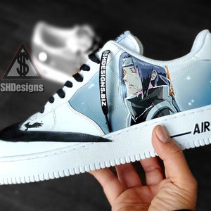 May include: White low-top sneakers with a black swoosh and a custom design featuring an anime character on the side. The text "SHDesigns.Biz" is printed on the black shoelace.