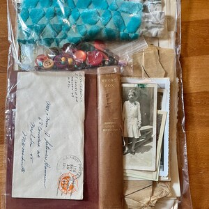 May include: A plastic bag filled with various items, including a book titled "The Wrong Box" by Robert Louis Stevenson, a vintage envelope with a U.S. Army postmark, a turquoise velvet fabric, and a collection of colorful buttons.