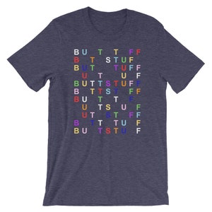Op de afbeelding: Een heidegrijs T-shirt met het woord "BUTT STUFF" herhaald in een rasterpatroon. Elke letter heeft een andere kleur.