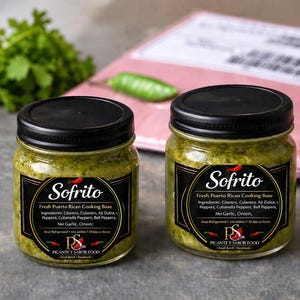Może przedstawiać: Dwa przezroczyste szklane słoiki wypełnione zieloną bazą do gotowania Sofrito, każdy z czarną nakrętką. Czarne etykiety zawierają napis Sofrito, Fresh Puerto Rican Cooking Base oraz listę składników, w tym kolendrę i paprykę.