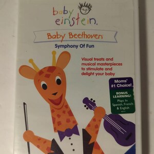 May include: A DVD cover featuring a cartoon giraffe wearing a tuxedo and playing a violin. The title is "Baby Beethoven: Symphony of Fun" with the Baby Einstein logo. The cover also states "Moms' #1 Choice!" and "Bonus Learning! Plays in Spanish, French & English".