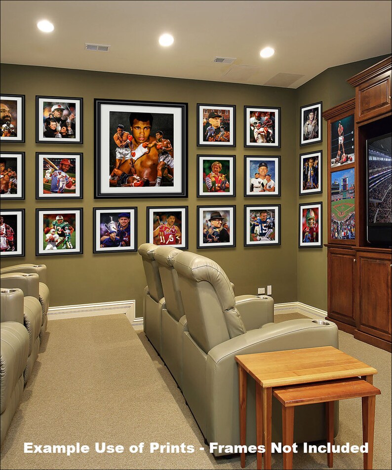 May include: A home theater room with a wall of framed sports and boxing prints, two beige reclining chairs, and two end tables. The room has a brown carpet and a brown entertainment center with a television.