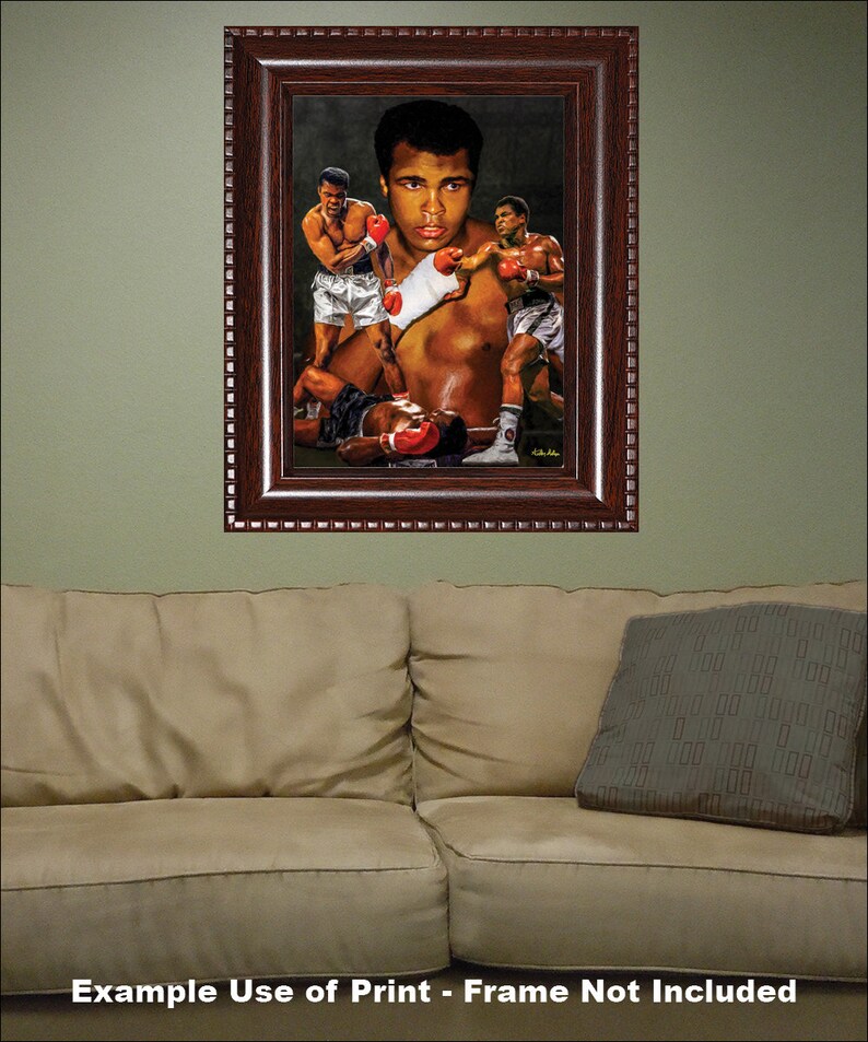 May include: A framed painting of a boxing match featuring Muhammad Ali. The painting depicts Ali in a dynamic pose, throwing a punch, with two other boxers in the background. The painting is set against a dark background and is framed in a dark wood frame.