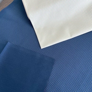 May include: Two pieces of fabric, one white with small blue dots and one dark blue with small white dots.