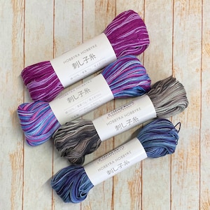 May include: Four spools of colorful embroidery floss, each with a label that reads "Hobbyra Hobbyre 刺し子糸" (meaning "Hobbyra Hobbyre Sashiko Thread"). The labels also include the weight and length of the thread in grams and meters.