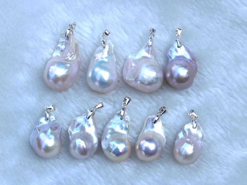 May include: Ten white and iridescent baroque pearl pendants with silver bail settings. The pearls are various shapes and sizes.