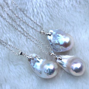 May include: Three silver chains with baroque pearl pendants. The pearls are white with iridescent hues.