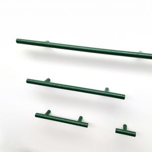 Peut inclure: Un ensemble de quatre poignées de placard vert forêt de longueurs variables, chacune présentant un design en barre cylindrique avec deux points de fixation, sauf la plus petite qui a un seul point de fixation central, finition lisse.