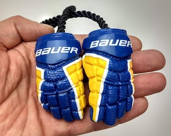 May include: A pair of blue and yellow hockey glove keychains with the word "Bauer" printed on each glove.