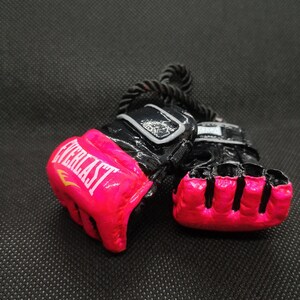 May include: A pair of pink and black Everlast boxing gloves with a black rope attached.