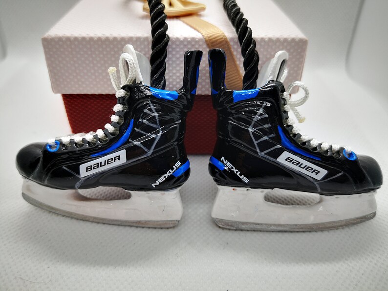 May include: A pair of black and blue hockey skate ornaments with white laces and the words "Bauer" and "Nexus" on them.