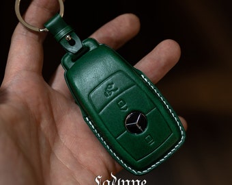 May include: Green leather car key fob cover with white stitching and a silver key ring. The cover features the Mercedes-Benz logo and is embossed with key symbols. The Ladnne Craft Atelier logo is visible at the bottom.