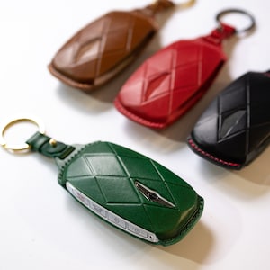 May include: Four key fobs in different colors: brown, red, black, and green. Each fob has a diamond-shaped pattern and a metal ring.