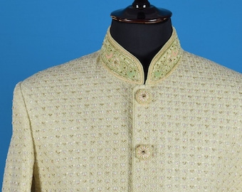 May include: A cream-coloured blazer with a mandarin collar and gold embroidery. The blazer has a textured fabric and three buttons down the front.