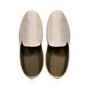 Peut inclure: Une paire de pantoufles en soie beige &agrave; bout pointu et &agrave; dos ferm&eacute;.