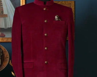 May include: A maroon velvet blazer with a mandarin collar and gold buttons. The blazer has a pocket on the left side with a patterned handkerchief.