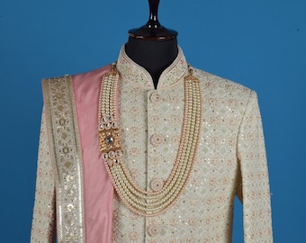 May include: A white and pink embroidered men's garment with a pearl and gold necklace. The garment has a high collar and long sleeves.