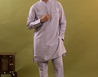 Pode incluir: Conjunto kurta e calças roxo claro. A kurta de manga comprida tem gola mandarim, dois bolsos no peito e fecho de botões. As calças são de perna reta. O conjunto é feito de tecido leve, estilo tradicional.
