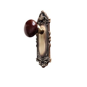 May include: A vintage-style door knob with an ornate brass plate and a dark brown ceramic knob.