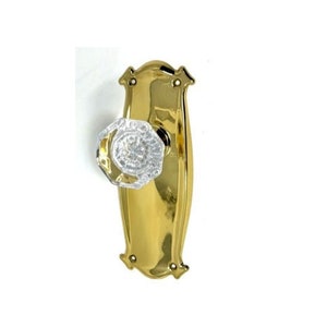 May include: A vintage-style door handle with a clear, faceted crystal knob and a polished brass backplate. The backplate has decorative edges and mounting holes. This hardware is suitable for interior doors.
