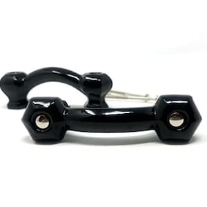 May include: Two black cabinet pulls with a glossy finish. One pull is a curved handle, and the other is a rectangular shape with hexagonal ends. Each has a silver-colored screw head.