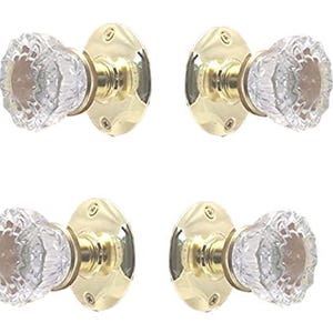 May include: A set of four door knobs featuring clear, faceted glass handles attached to polished brass circular backplates. Each knob has a central brass core visible through the glass, with screws integrated into the mounting plates.