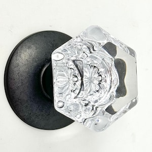 May include: A clear glass door knob with a decorative pattern, mounted on a black metal base.