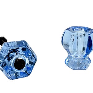 May include: Two blue glass cabinet knobs with a hexagonal shape. One knob has a black screw, the other has a smooth base.