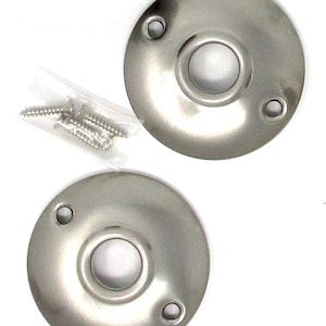 May include: Two circular, brushed nickel metal plates with a central opening and two smaller screw holes on opposite sides. A small, clear plastic bag containing four silver-colored metal screws is included with the hardware components.