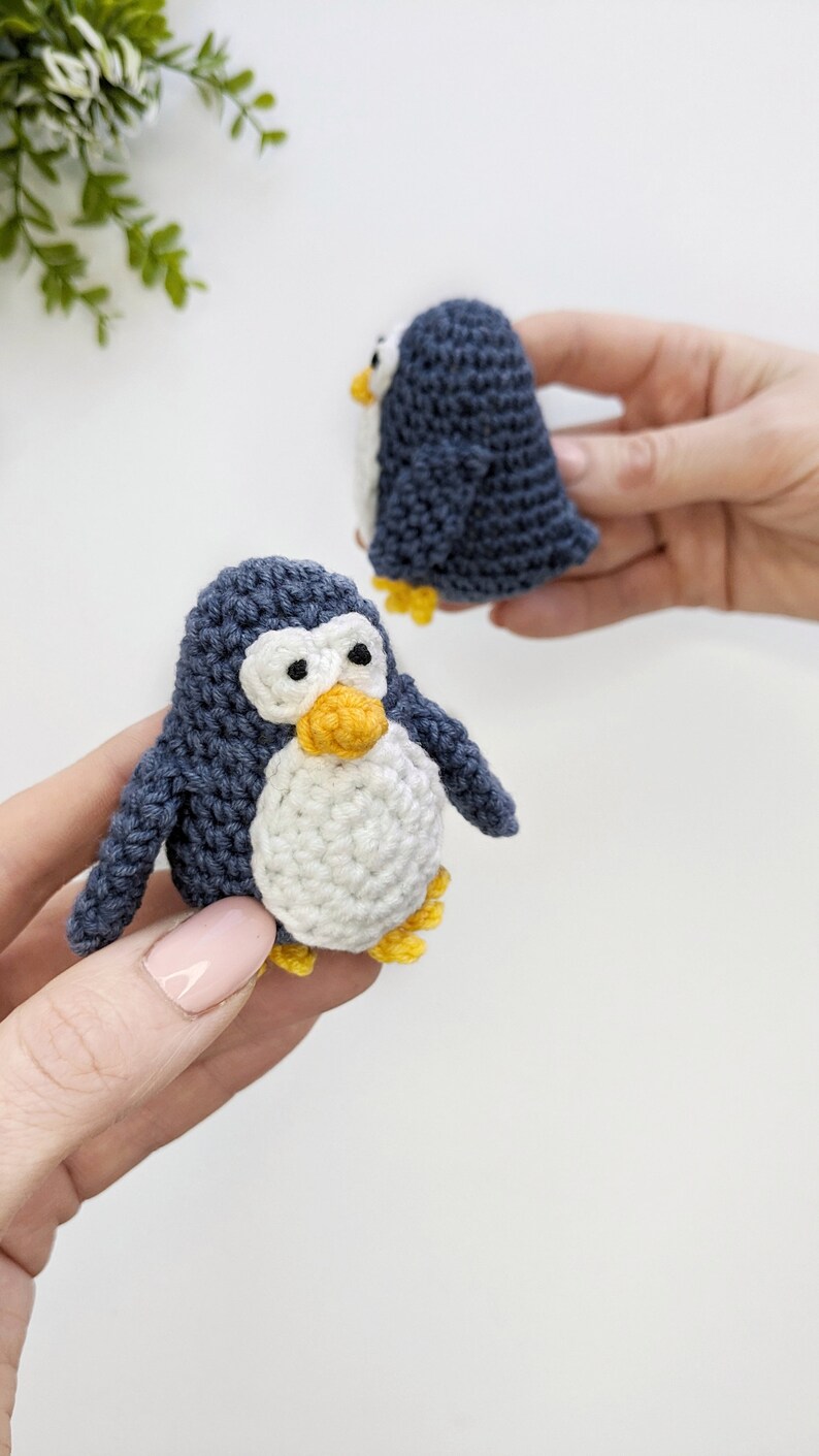 Pode incluir: Dois brinquedos de pinguim de croch&ecirc;. Um pinguim &eacute; azul com a barriga branca e o bico e as patas amarelas. O outro pinguim &eacute; azul com o bico e as patas amarelas.