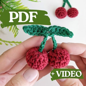 Puede incluir: Patrón de crochet para un par de cerezas rojas con hojas verdes. El patrón incluye instrucciones en PDF y video.