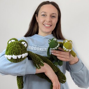 Puede incluir: Juguetes de peluche de cocodrilo verde tejidos a ganchillo con detalles blancos. La imagen muestra tres juguetes de cocodrilo de diferentes tama&ntilde;os. Los juguetes tienen un aspecto suave y texturizado. Los juguetes de cocodrilo son un art&iacute;culo divertido y caprichoso.