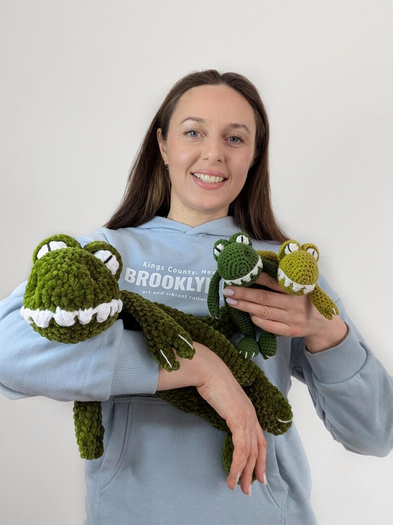 Puede incluir: Juguetes de peluche de cocodrilo verde tejidos a ganchillo con detalles blancos. La imagen muestra tres juguetes de cocodrilo de diferentes tama&ntilde;os. Los juguetes tienen un aspecto suave y texturizado. Los juguetes de cocodrilo son un art&iacute;culo divertido y caprichoso.