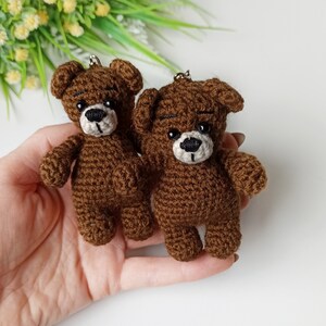 May include: Two brown crocheted teddy bear keychains with black eyes and white noses.