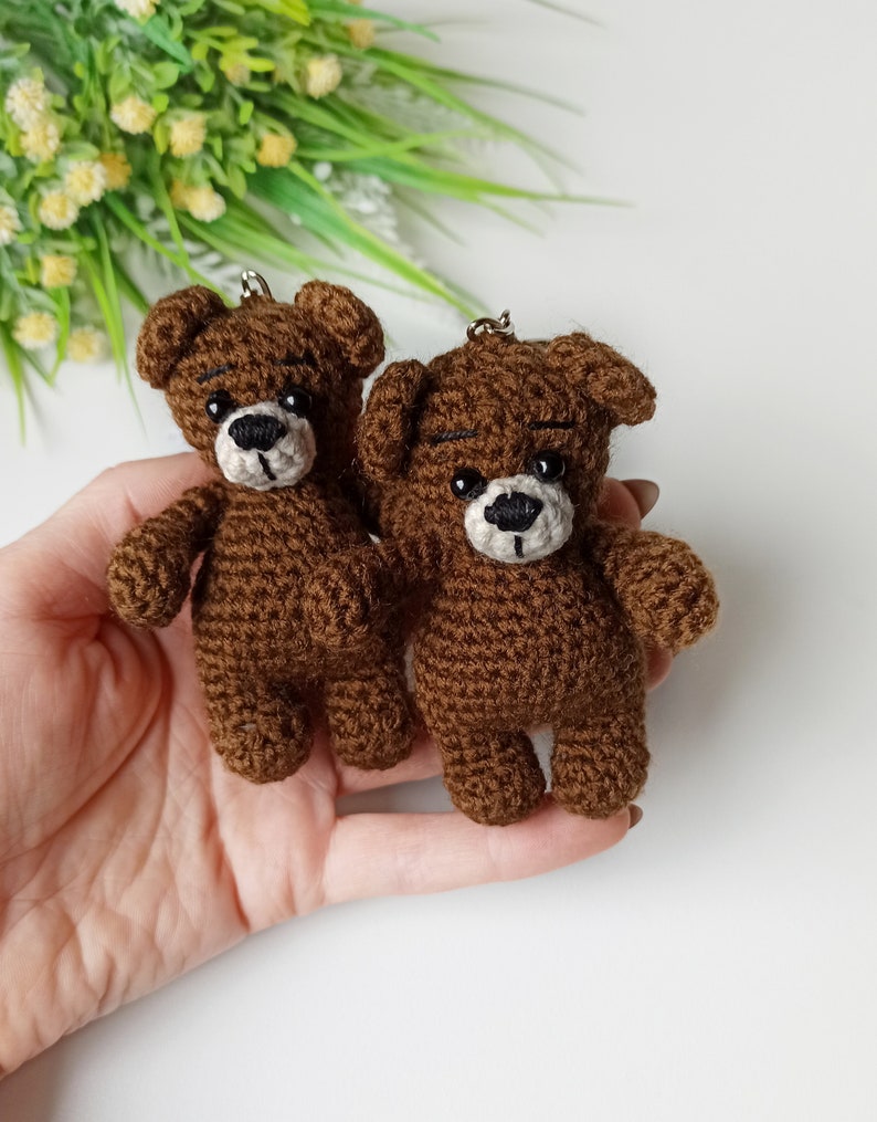 May include: Two brown crocheted teddy bear keychains with black eyes and white noses.