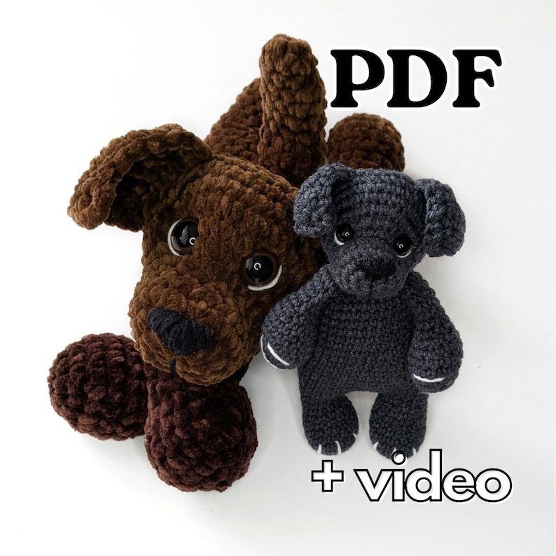 K&ouml;nnte beinhalten: Zwei geh&auml;kelte Hunde-Stofftiere, ein gro&szlig;es braunes und ein kleineres dunkelgraues, beide mit gro&szlig;en schwarzen Kunststoffaugen und schwarzen gestickten Nasen. Der Text PDF und + video ist sichtbar und weist auf digitale Anleitungen hin.