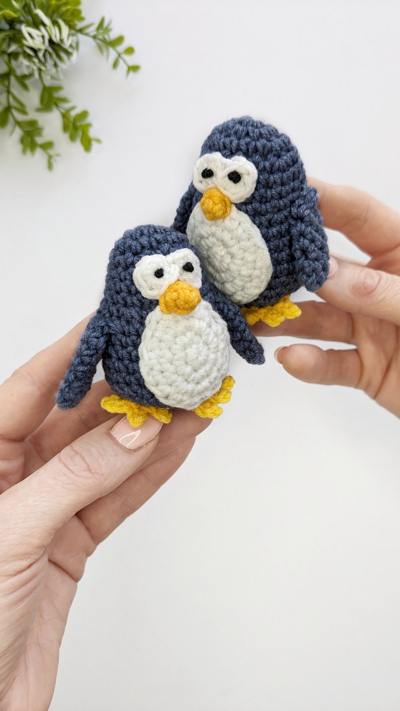Pode incluir: Dois pequenos brinquedos de pinguim de croch&ecirc;. Os pinguins s&atilde;o azuis com barrigas brancas e bicos e p&eacute;s amarelos.