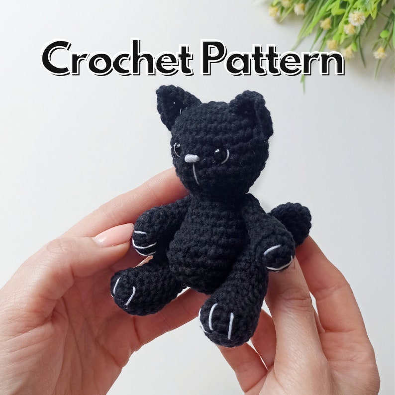 May include: A black crocheted cat amigurumi toy with white details on the face and paws. Crochet Pattern.
