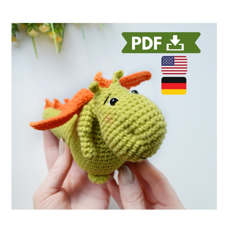 May include: Crochet pattern PDF for a green and orange dragon amigurumi toy. The pattern is available in English and German.