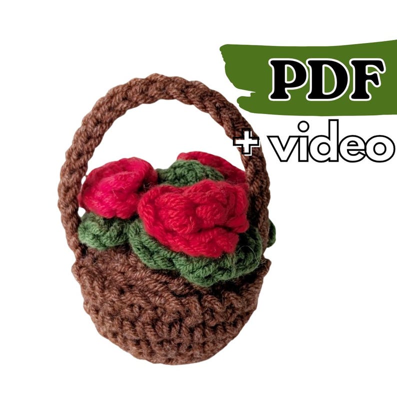 May include: A crocheted brown basket with a handle, filled with red roses and green leaves. The text "PDF + video" is in the upper right corner. This handmade item is perfect for home decor or as a unique gift.