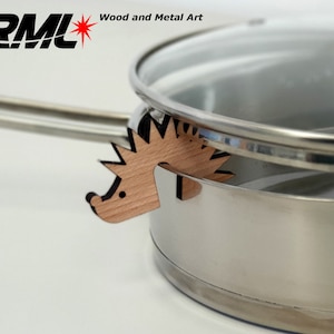 Op de afbeelding: Een houten egel potdekselhouder in natuurlijke houttinten. De houder is ontworpen om een potdeksel open te houden.