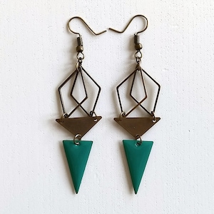 Peut inclure: Une paire de boucles d'oreilles géométriques avec une finition dorée. Les boucles d'oreilles présentent une forme de diamant superposée avec un pendentif triangulaire et un plus petit pendentif triangulaire vert.