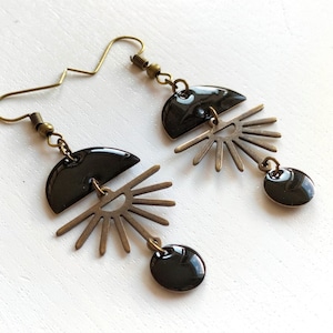 May include: A pair of black and gold earrings with a geometric design. The earrings feature a half-circle shape with a sunburst design.