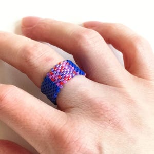 Peut inclure: Une bague en perles bleues avec un motif géométrique rose et rouge.